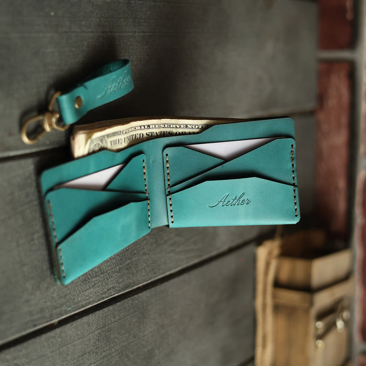 Aether blue leather bifold wallet open flat with cards and keychain