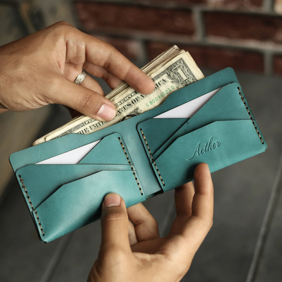 Cash being placed into the Aether blue leather bifold wallet