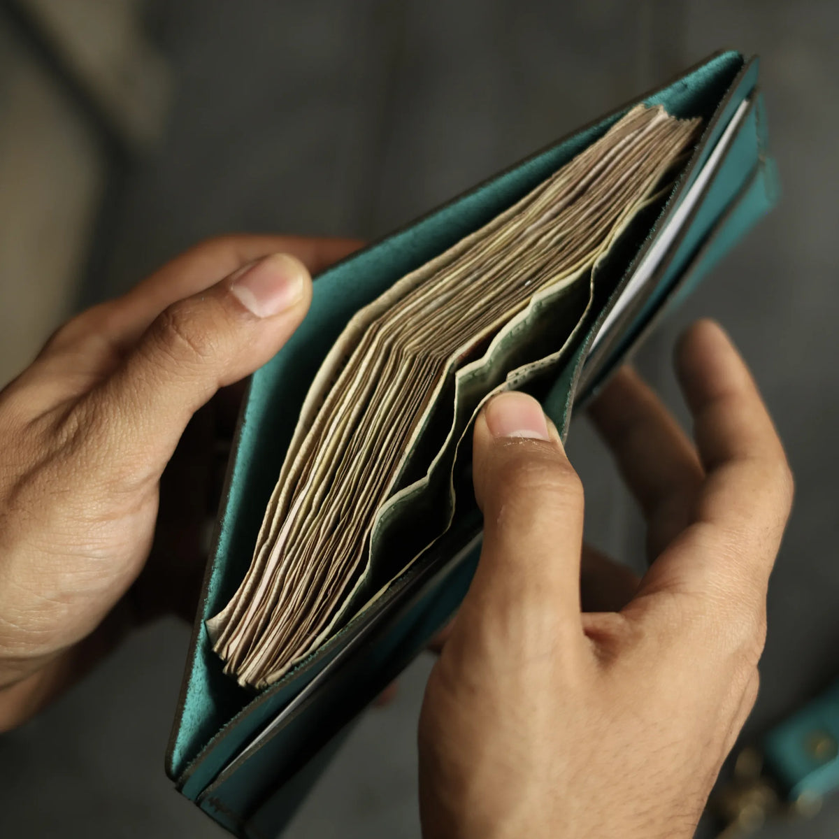 Aether blue leather bifold wallet holding a full stack of notes