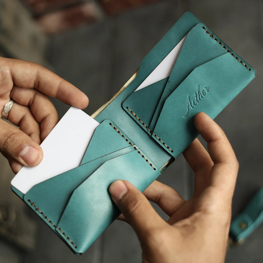 Aether blue leather bifold wallet held open in both hands